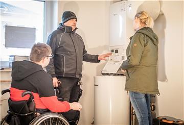 Anlagenmechaniker Robert Wagner erklärt Marvin und Yvonne Holst die Heizungsanlagensteuerung.