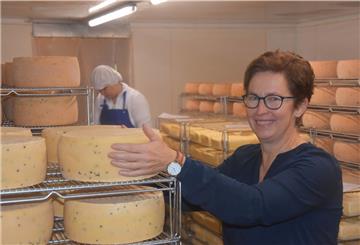 Frau steht in einem Lagerraum mit Käse.