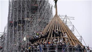 Arbeiter feiern den Abschluss des Wiederaufbaus des Dachstuhls der Kathedrale Notre Dame mit einem traditionellen Blumenstrauß.