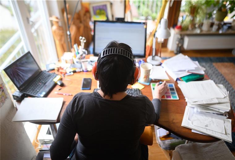 Bald Mindestanspruch auf 24 Tage Homeoffice? Frau mit Kopfhörern an Schreibtisch