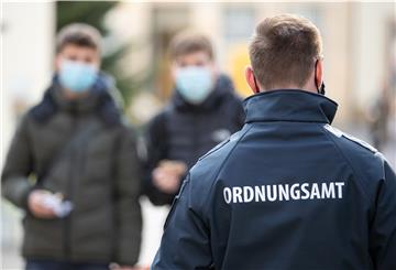 ARCHIV - 04.11.2020, Nordrhein-Westfalen, Bielefeld: Ein Mitarbeiter vom Ordnungsamt patrouilliert in der Fußgängerzone an Passanten vorbei, die Mund-Nase-Bedeckung tragen. Seit Beginn der Pandemie haben viele Städte tausende Verstöße registriert und hohe Bußgeldsummen eingenommen. (zu dpa «NRW-Städte haben bereits Corona-Bußgelder in Millionenhöhe verhängt») Foto: Friso Gentsch/dpa +++ dpa-Bildfunk +++