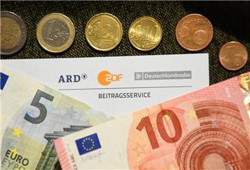 Mehrere Geldscheine und Münzen liegen auf einem Tisch. In er Mitte ist ein Schreiben vom Beitragsservice.