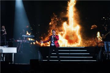 Armando Sarowny mit einer Gitarre in Flammen.