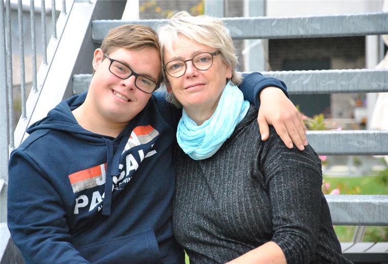 Leon aus Zeven steht mit Tim Mälzer vor der Kamera Astrid Dohrmann und ihr Sohn Leon sitzen auf einer Stahltreppe. Leon legt den Arm um seine Mutter und lächelt.