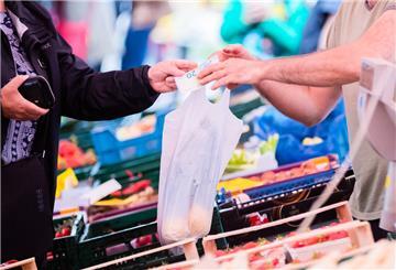 Eine Kundin bezahlt auf einem Wochenmarkt an einem Obst- und Gemüsestand.