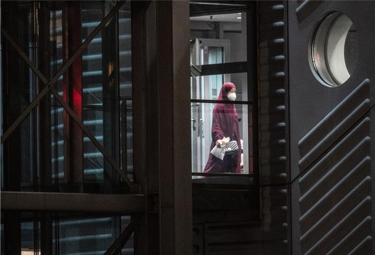 Eine verschleierte Frau mit einer Maske betritt aus der Gangway einer Chartermaschine heraus einen abgeschirmten Bereich der Bundespolizei am Flughafen Frankfurt. 