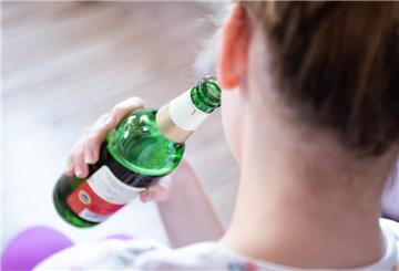  Ein Mädchen hält in ihrem Zimmer eine Flasche Bier.