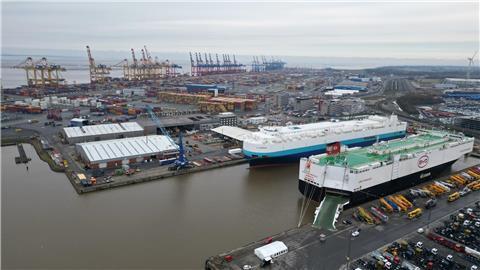 Auf dem Bild ist das Autoterminal in Bremerhaven zu sehen, im Hintergrund stehen Kräne des Containerterminals.