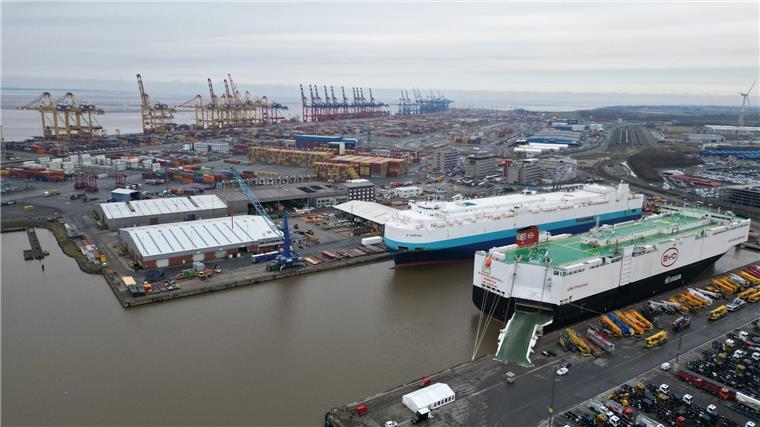 Auf dem Bild ist das Autoterminal in Bremerhaven zu sehen, im Hintergrund stehen Kräne des Containerterminals.