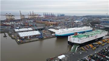Auf dem Bild ist das Autoterminal in Bremerhaven zu sehen, im Hintergrund stehen Kräne des Containerterminals.