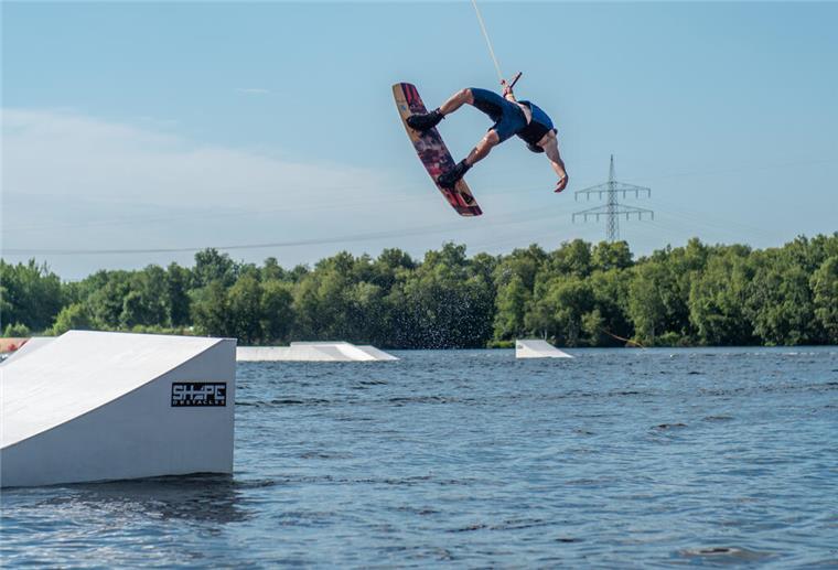Ein Wakeboarder springt bei einer Fahrt auf dem Spadener See.