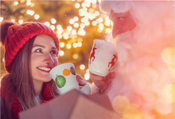 Frau prostet Weihnachtsmann mit Tasse zu