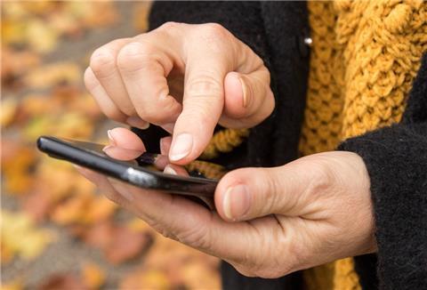 Frauenhände halten ein Handy und tippen auf den Bildschirm.