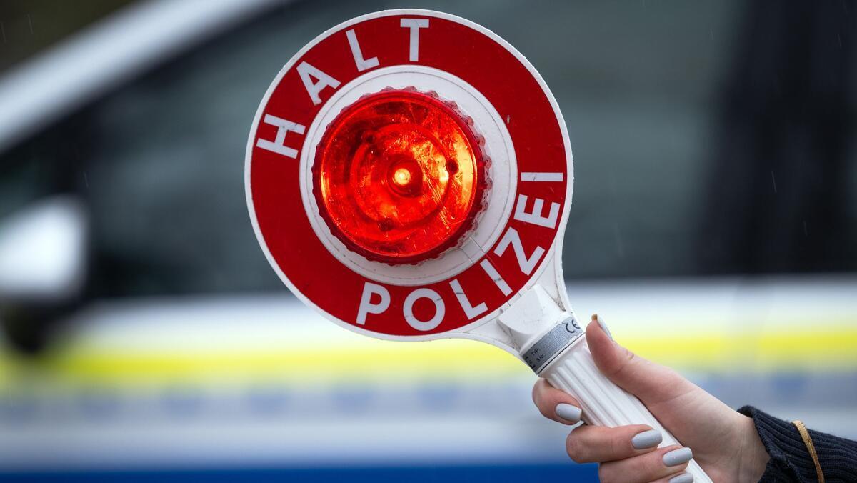 Raser fliegt mit Drogen auf – und will mit falschem Penis beim Urin-Test tricksen Eine Polizistin hält während einer Verkehrskontrolle eine Polizeikelle mit der Aufschrift „Halt Polizei“.