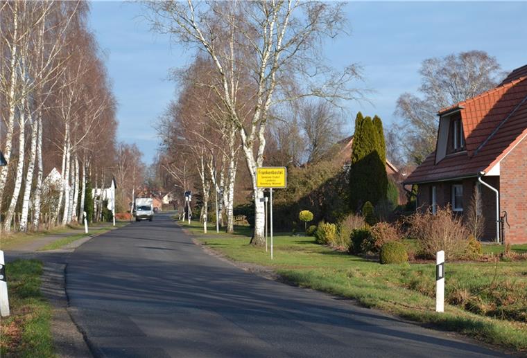 Ein Kleintransporter fährt auf einer Dorfstraße an Wohnhäusern vorbei