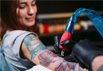Eine Frau lässt sich tätowieren und lächelt dabei. In Bremerhaven findet am 15. und 16. März eine Tattoo-Messe statt, die sich an Frauen richtet. 