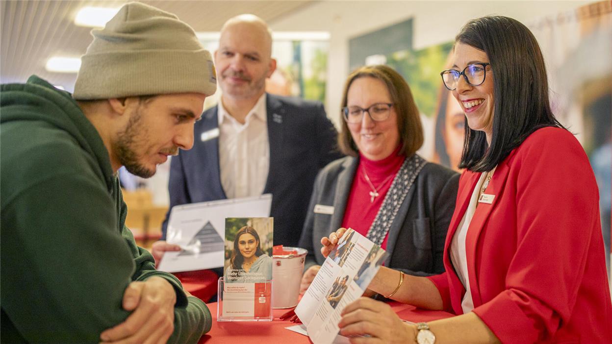 Beratungssituation: Ein junger Mann mit Mütze informiert sich an einem Stand