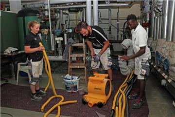Auf Dominik Duden (Mitte) und die beiden Azubis Lina Maack (links) und Kaira Sidibeh wartet eine schweißtreibende Aufgabe, denn sie müssen den Wasserspeicher des Spaßbeckens in Zeven abschleifen und mit einer neuen Chlor-Kautschuk-Schicht streichen.
