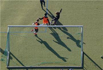 Kinder spielen Fußball auf einem Kunstrasenplatz.
