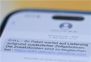 Auf einem Smartphone ist eine Betrugs-SMS zu lesen, in der Kriminelle ein Paket ankündigen und dafür Zollgebühren einfordern.