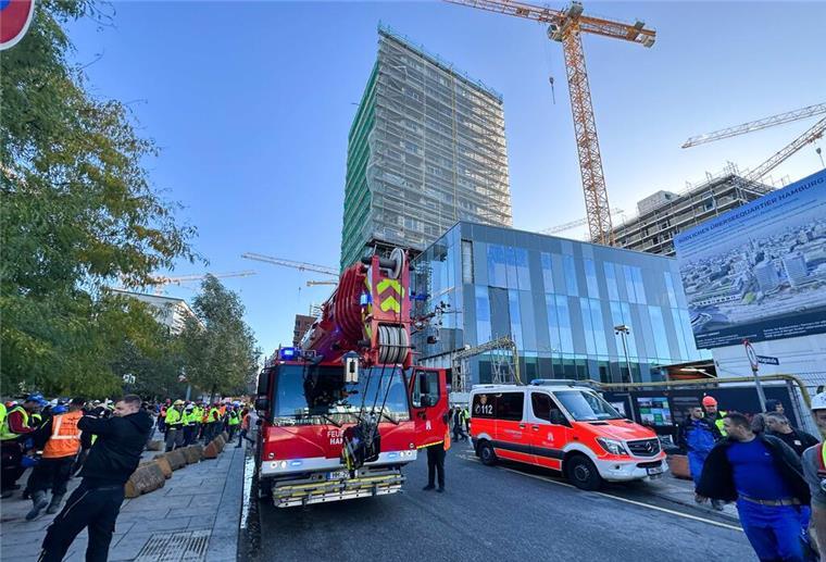 Vier Tote auf Hamburger Baustelle: Gerüst stürzt in Fahrstuhlschacht Einsatzfahrzeuge der Feuerwehr stehen vor einem eingerüsteten Hochhaus.