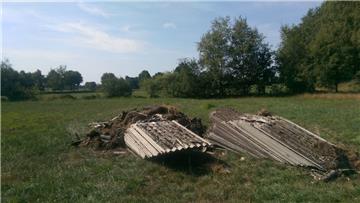 Auf einer Wiese bei Byhusen sind zwei große Haufen Eternitplatten abgeladen worden.