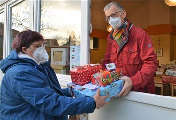 Mann und Frau mit Geschenken an einem Fenster.