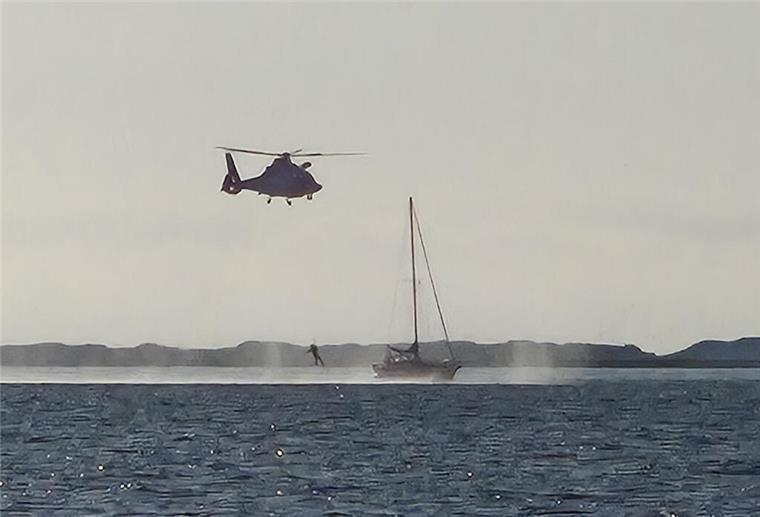 Aufnahme vom Seenotrettungsboot „Fritz Thieme“ aus: Mit dem Hubschrauber wird ein Notfallsanitäter auf dem Segelboot absetzt.