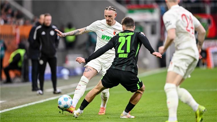 Augsburgs Marius Wolf spielt den Ball an Joakim Maehle von Wolfsburg vorbei.