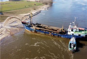 Aus dem Laderaum des Schiffes wird Sand auf den Strand gespült.