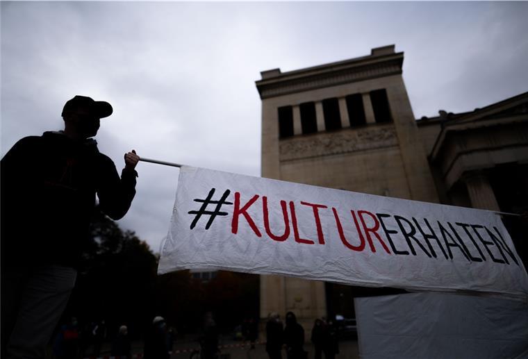 Mehr Sicherheit für Kulturschaffende Zwei Männer auf Stelzen halten auf dem Königsplatz ein Banner mit der Aufschrift «#KulturErhalten».