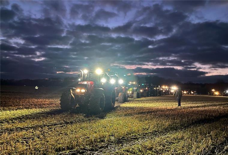 Beleuchtete Traktoren fahren zur Abendzeit auf eine Weide