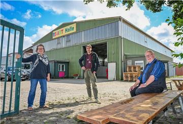 Drei Personen vor einer Halle