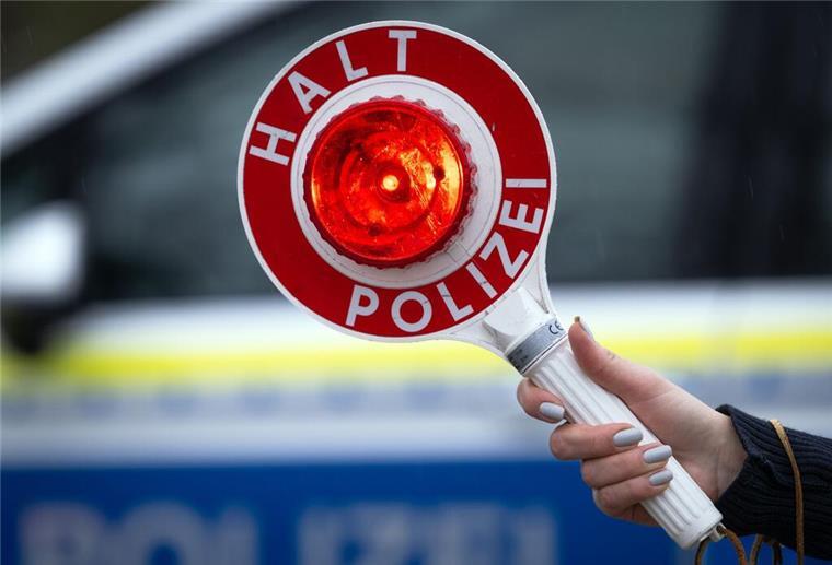Eine Polizistin hält während einer Verkehrskontrolle eine Polizeikelle mit der Aufschrift „Halt Polizei“