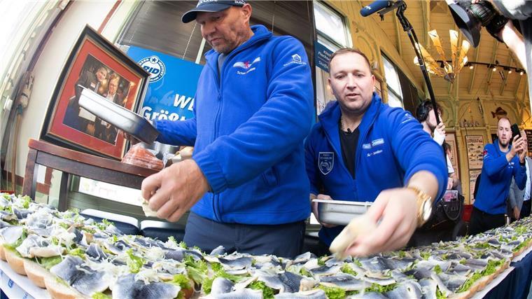 Usedomer schafft Weltrekord mit gigantischem Fischbrötchen Axel Schulz, ehemalige Profiboxer (l-r), und André Domke Fischsommelier und Fischhändler belegen das gigantische Fischbrötchen mit Salat, Fisch und Zwiebeln.