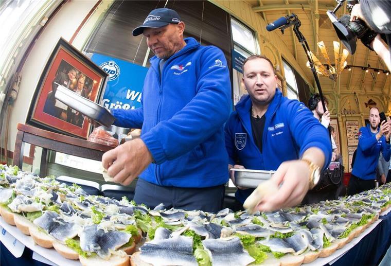 Usedomer stellt neuen Rekord für das längste Fischbrötchen auf Axel Schulz, ehemalige Profiboxer (l-r), und André Domke, Fischsommelier und -händler, belegen das gigantische Fischbrötchen mit Salat, Fisch und Zwiebeln.