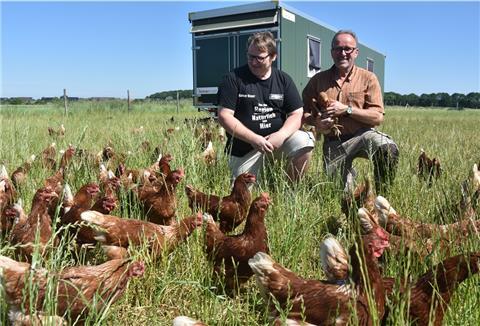 Das Bild zeit Landwirt Hans Peter Meinke und Bäckermeister inmitten einer Hühnerschar.  