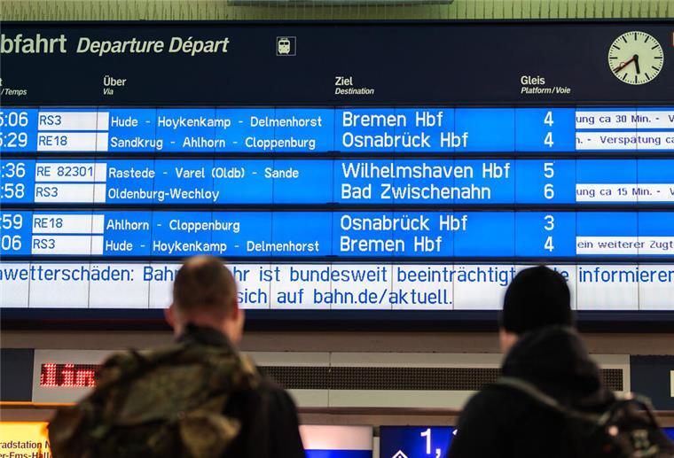 EU-Verordnung: Bahn muss bei Verspätungen durch Notfälle nicht mehr zahlen Zwei Reisende stehen am Morgen am Oldenburger Hauptbahnhof und schauen zur Anzeigetafel