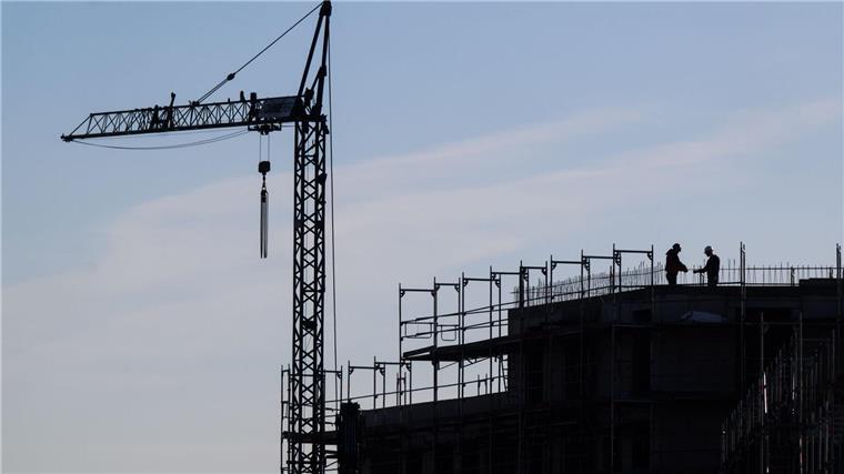 Bauarbeiter stehen auf der Baustelle eines Mehrfamilienhauses.