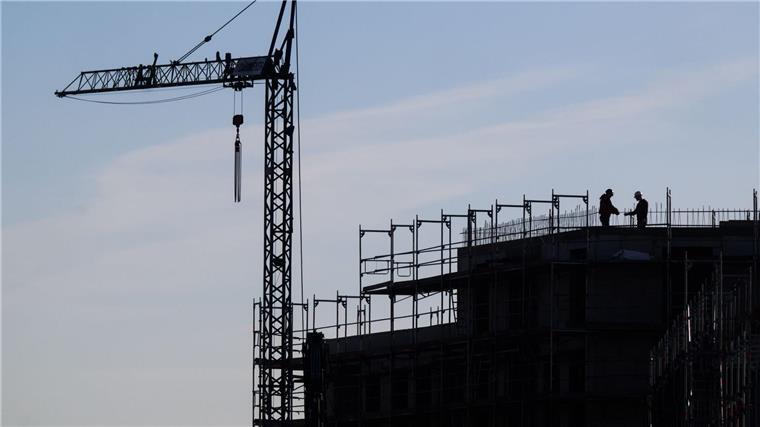 Verband fordert mehr öffentliche Förderung im Wohnungsbau Bauarbeiter stehen auf der Baustelle eines Mehrfamilienhauses.