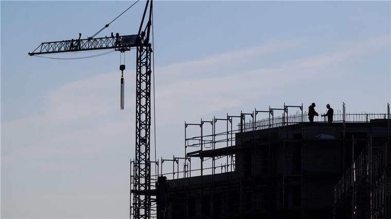 Bauarbeiter stehen auf der Baustelle eines Mehrfamilienhauses.