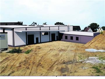 Baucontainer (links) und Sandhaufen (rechts) muss man sich wegdenken: Unsere Fotomontage zeigt, wie Mühlenbecks neue Halle in Spaden mal aussehen wird.