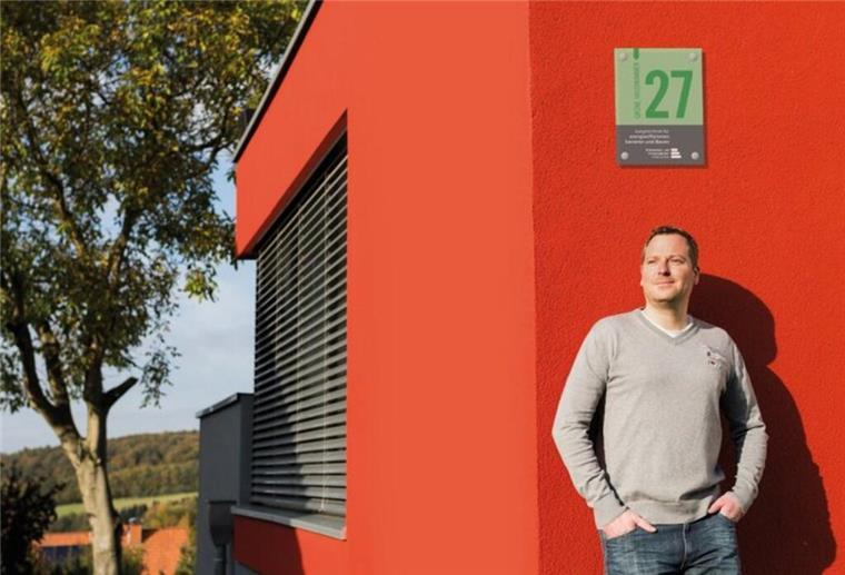 Mann lehnt entspannt an einer orangen Hauswand