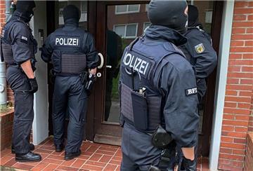 Beamte der Bundespolizei stehen vor einer Haustür.