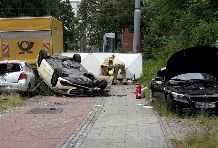 Bremen: Taxi rast los und überschlägt sich Ein stark beschädigter Taxi-Wagen liegt auf dem Dach nahe einer Straße. Weitere Fahrzeuge stehen mit deutlichen Schäden in der Nähe.