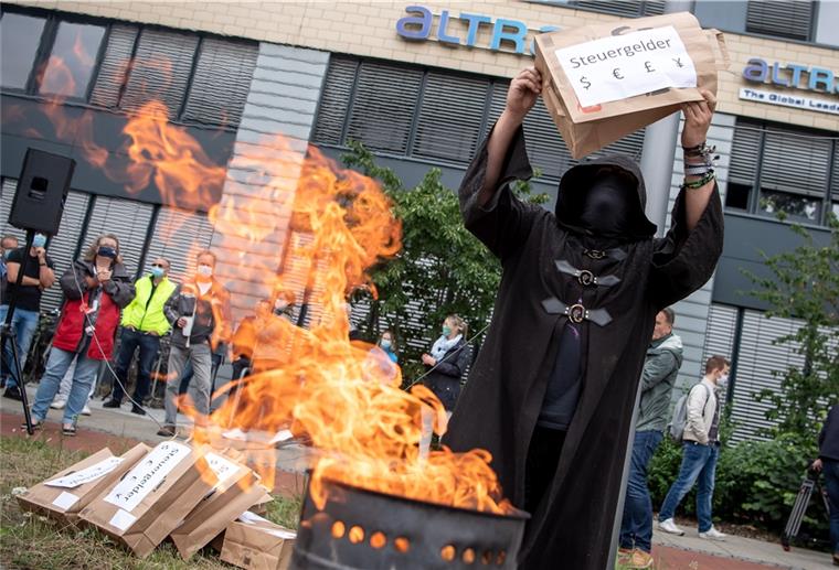 Bei einer Protestkundgebung der IG Metall in Bremen schmeißt ein Mann vor dem Airbus-Werk eine Tüte in eine Feuertonne.