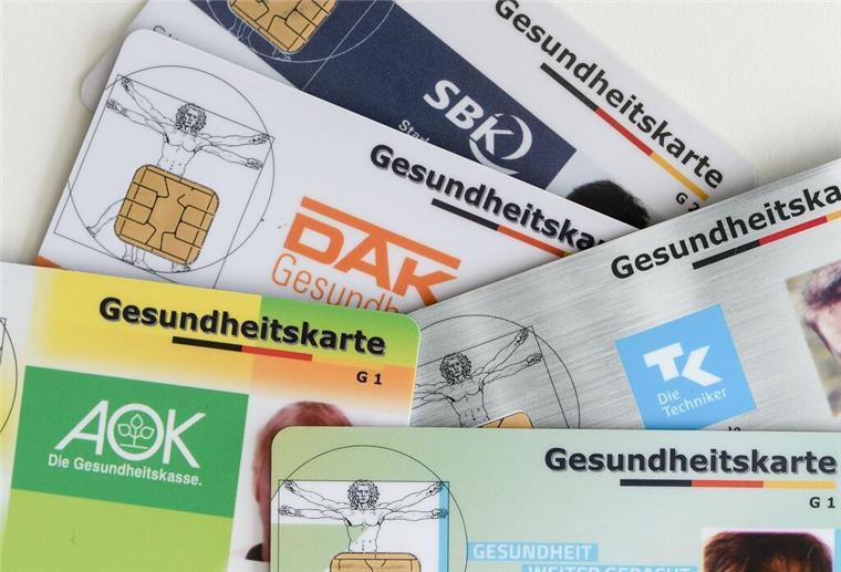 Gesundheitskarten verschiedener Krankenkassen liegen auf einem Tisch.