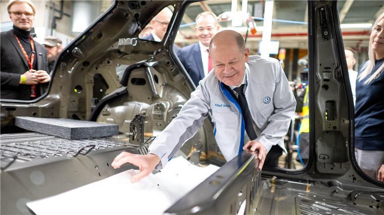 Bei seinem Besuch im Emder VW Werk hilft Bundeskanzler Olaf Scholz (SPD) beim Einbau einer Dämmmatte. 