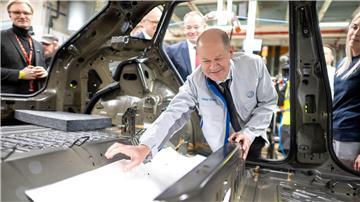 Bei seinem Besuch im Emder VW Werk hilft Bundeskanzler Olaf Scholz (SPD) beim Einbau einer Dämmmatte. 
