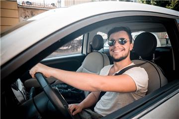 Junger Mann fährt silbernes Auto.